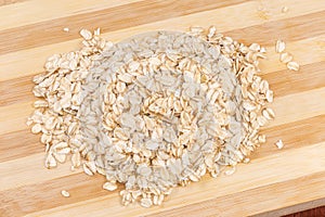 Raw thick-rolled oats on wooden cutting board close-up