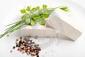 Raw tofu cubes with spices and herbs on white plate