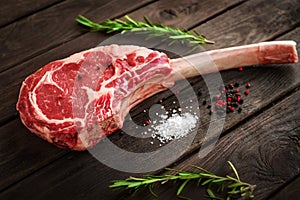 Raw Tomahawk steak on wooden background with spices for grilling