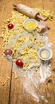 Raw tomatoes and pasta with flour, eggs and salt wooden rustic background top view close up