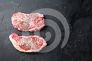 Raw top blade steak cuts, top view on black textured background with space for text