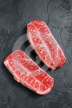 Raw top blade steak dry-aged. Black background. Top view