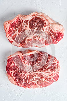 Raw top blade steak. Organic beef. White textured background. Top view