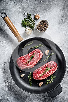 Raw top-blade steak in a pan. Gray background. Top view