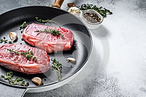 Raw top-blade steak in a pan. Gray background. Top view. Copy space