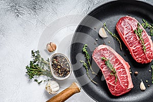 Raw top-blade steak in a pan. Gray background. Top view. Copy space