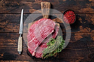 Raw top sirloin cap steak or Picanha steak on wooden board with thyme. Dark wooden background. Top view