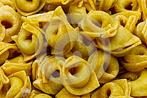 Raw Tortellini in a wooden bowl on wooden table. Traditional italian pasta.