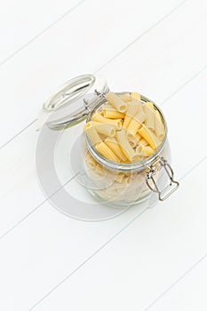 Raw tortiglioni pasta on a glass jar