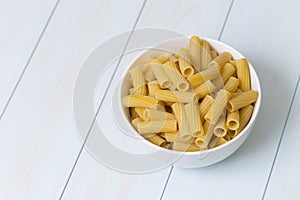 Raw tortiglioni pasta in a white bowl