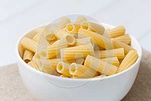 Raw tortiglioni pasta in a white bowl