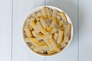 Raw tortiglioni pasta in a white bowl