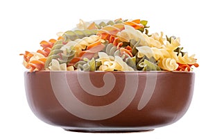 Raw tricolor fusilli or rotini pasta in clay bowl isolated on white background. File