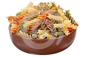 Raw tricolor fusilli or rotini pasta traditional, tomato and spinach taste in clay bowl isolated on white background. File