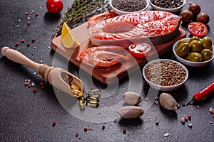 Raw trout red fish steak served with herbs and lemon and olive oil on a dark background