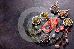 Raw trout red fish steak served with herbs and lemon and olive oil on a dark background