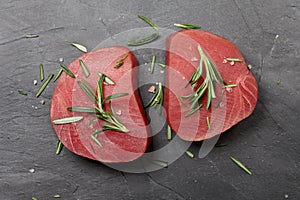 Raw tuna steak with rosemary on black stone