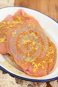 Raw turkey with spices on white dish