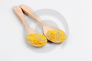 Raw turmeric powder on two wooden spoons