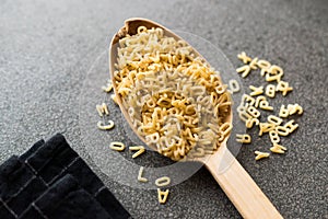 Raw Uncooked Alphabet Pasta in Wooden Spoon