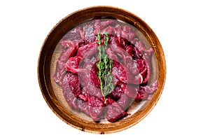 Raw uncooked beef meat sliced in strips with fresh herbs for beef stroganoff. Isolated on white background.