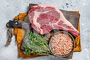 Raw uncooked black angus beef cowboy or rib eye steak. Gray background. Top view