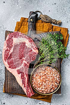 Raw uncooked black angus beef cowboy or rib eye steak. Gray background. Top view