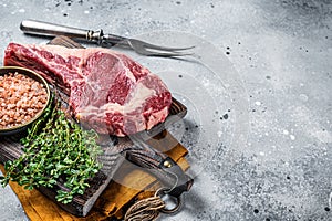 Raw uncooked black angus beef cowboy or rib eye steak. Gray background. Top view. Copy space