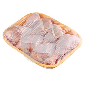 Raw and uncooked chicken drumsticks in a yellow plastic container. Meat of poultry in tray, isolated on white background