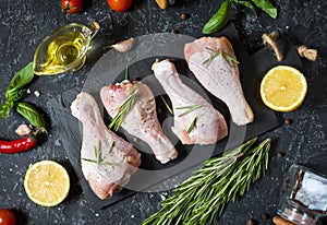 Raw uncooked chicken legs, drumsticks on stone board, meat with ingredients for cooking
