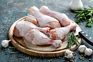 Raw uncooked chicken legs, drumsticks on wooden board, meat with ingredients