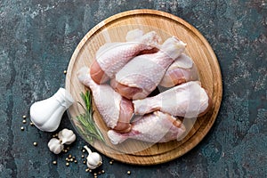 Raw uncooked chicken legs, drumsticks on wooden board, meat with ingredients for cooking