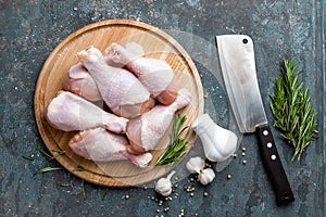 Raw uncooked chicken legs, drumsticks on wooden board, meat with ingredients for cooking