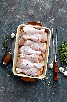 Raw uncooked chicken legs, drumsticks on wooden board, meat with ingredients for cooking