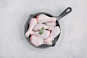 Raw uncooked chicken legs with rosemary  in cast iron pan