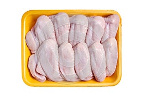 Raw and uncooked chicken wings in a yellow container. Meat of poultry in tray, isolated on white background. Top view