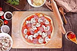 raw uncooked dough pizza and ingredients for pizza on the wooden background