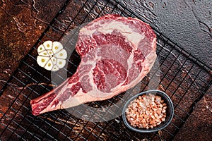 Raw uncooked dry aged beef tomahawk or rib eye steak. Dark background. Top view