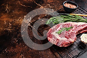 Raw uncooked dry aged beef tomahawk or rib eye steak. Dark background. Top view. Copy space