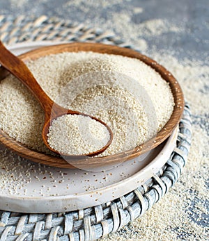 Raw uncooked fonio seeds with a spoon on a plate on grey background photo