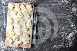 Raw uncooked homemade potato gnocchi with flour on cutting board