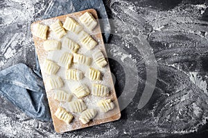 Raw uncooked homemade potato gnocchi with flour on cutting board.