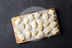 Raw uncooked homemade potato gnocchi with flour on cutting board.