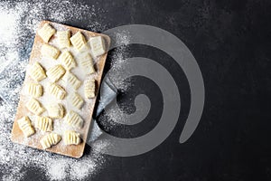 Raw uncooked homemade potato gnocchi with flour on cutting board. Top view.