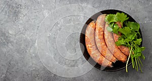 Raw uncooked meat sausages in a black iron pan.
