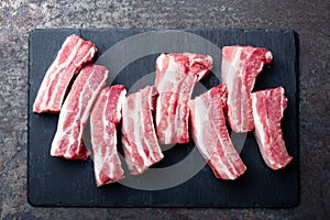 Raw uncooked pork ribs, fresh meat on dark metal background. Top view