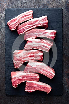 Raw uncooked pork ribs, fresh meat on dark metal background. Top view