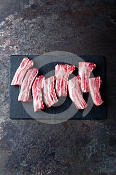 Raw uncooked pork ribs, fresh meat on dark metal background. Top view