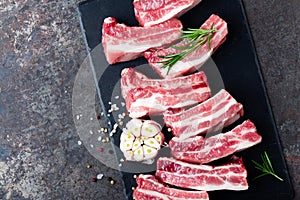 Raw uncooked pork ribs, fresh meat on dark metal background. Top view