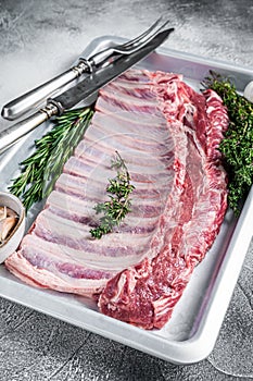 Raw uncooked rack of mutton lamb ribs in baking dish. White background. Top view